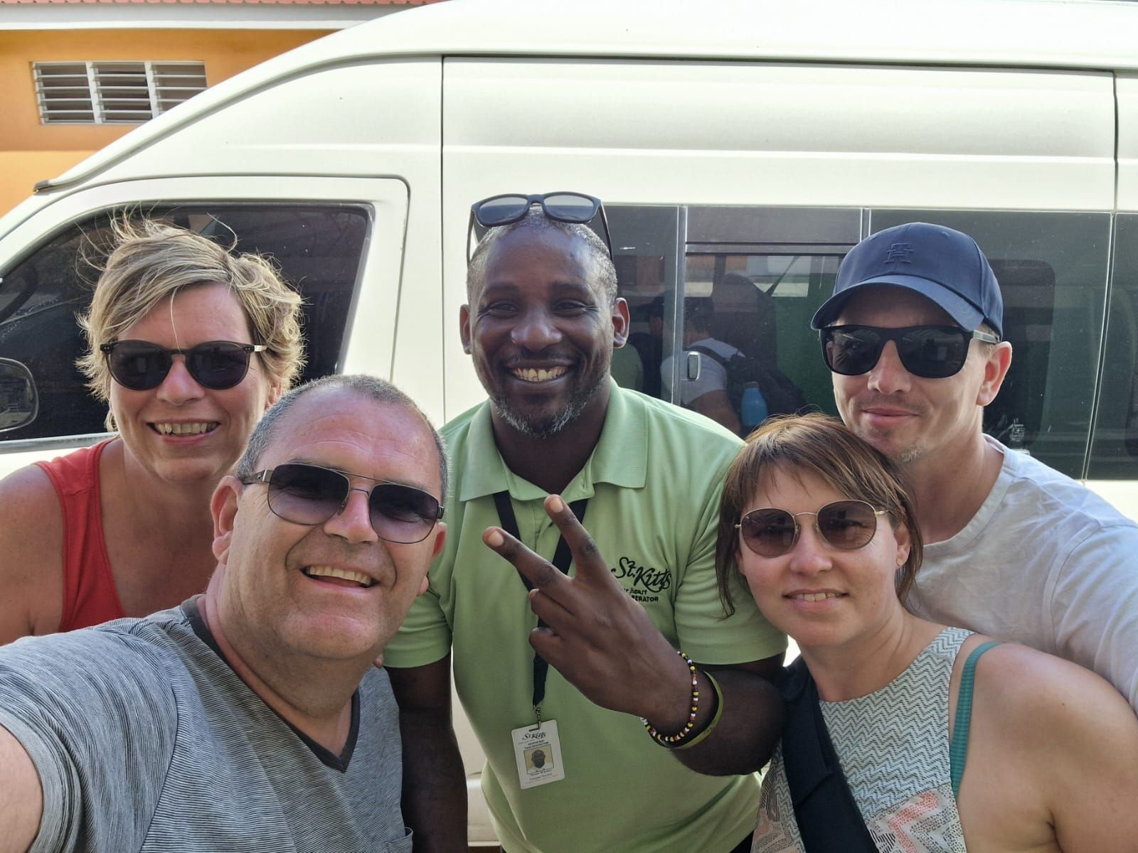 Group of five people smiling and posing in front of a white van, all wearing sunglasses.